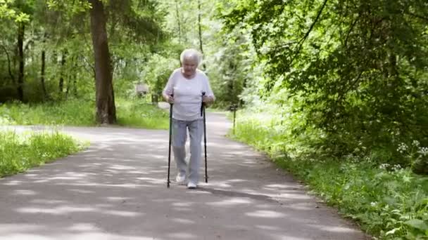 Oma spaziert mit Stöcken zum Nordic Walking in den Park