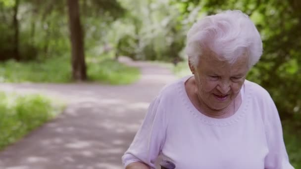 Oude oma gaat met stokken voor lopen op de weg — Stockvideo