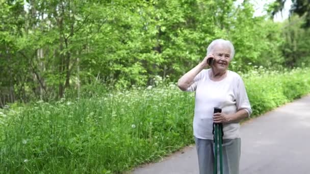 Седовласая бабушка разговаривает по телефону с семьей — стоковое видео