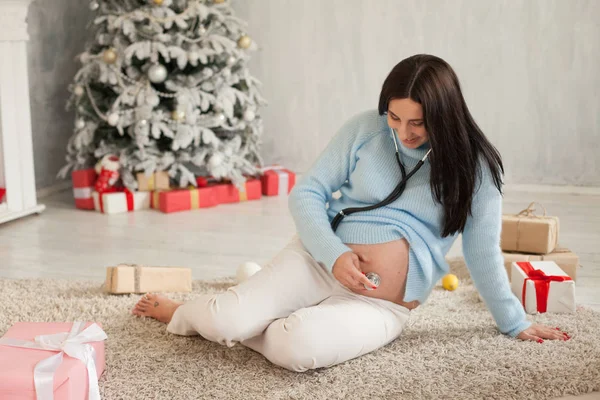 Pregnant woman listening to a baby in the belly stethoscope — Stock Photo, Image