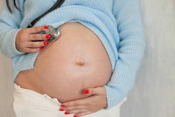 Pregnant woman listening to a baby in the belly stethoscope — Stock Photo, Image