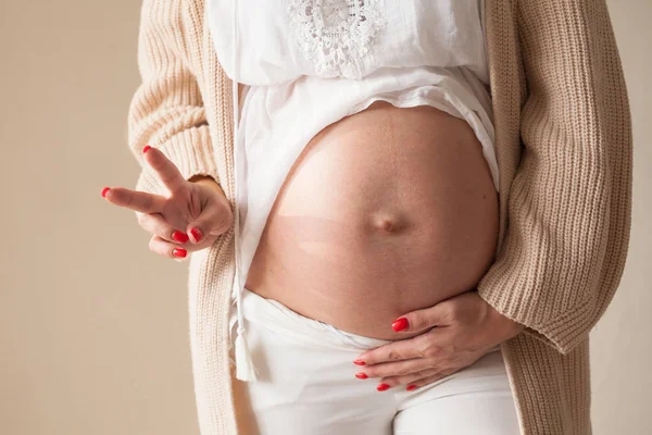 The stomach of a pregnant woman hand shows two fingers — Stock Photo, Image