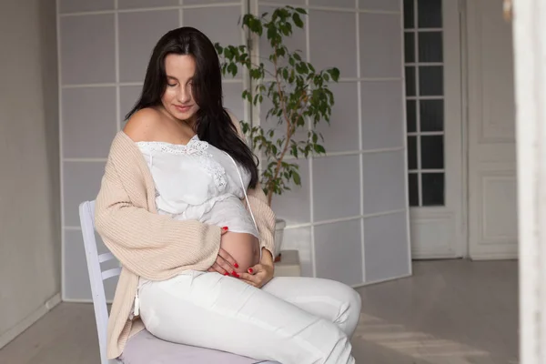 Mooie zwangere vrouw in een witte kamer — Stockfoto