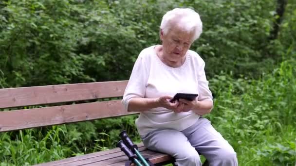Alte Oma schaut aufs Internet-Smartphone — Stockvideo
