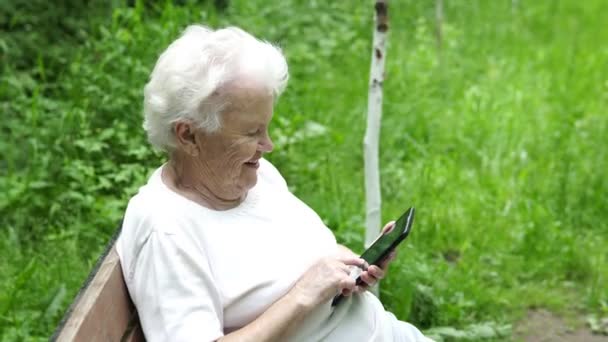 Velha avó olha para o smartphone Internet — Vídeo de Stock