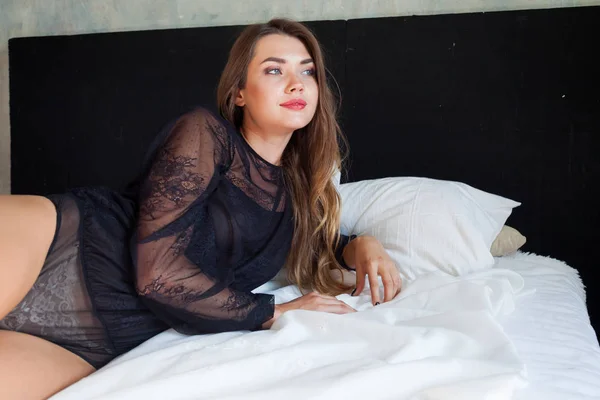 La mujer en ropa interior negro se encuentra en la cama en el dormitorio — Foto de Stock