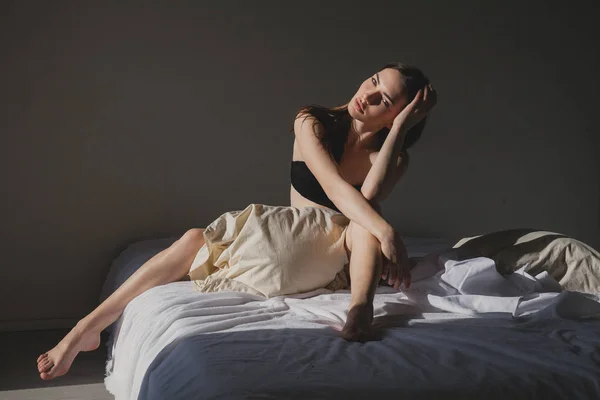 Mooie vrouw in ondergoed ligt op het bed in de slaapkamer vanavond — Stockfoto