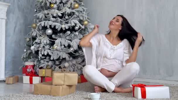 Беременная мама на елку смотрит рождественские подарки — стоковое видео