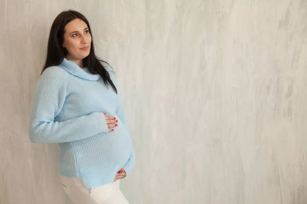 Portrét těhotné ženy v modré šaty šedé stěny — Stock fotografie