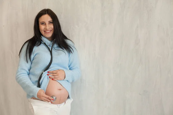 Těhotná maminka poslouchá stetoskopem žaludku — Stock fotografie