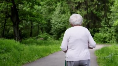 Büyükanne Nordic walking emeklilik için sopa ile parkta yürüyor