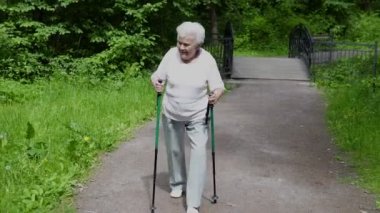 Büyükanne Nordic walking emeklilik için sopa ile parkta yürüyor