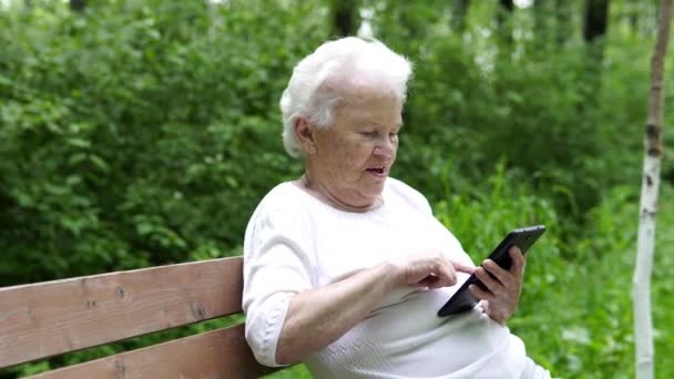 Stara babcia patrzy na Internet smartphone — Wideo stockowe