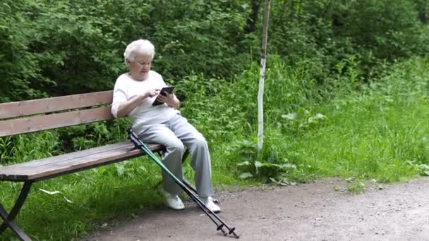 Vieja abuelita mira en el teléfono inteligente Internet — Vídeo de stock