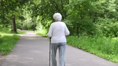 Yaşlı nine yolda yürürken için sopa ile gider