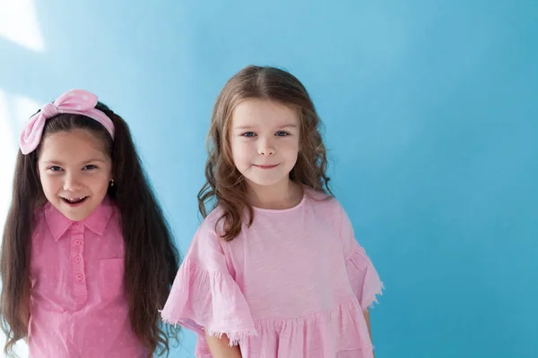 Two little girls girlfriends together on blue background — Stock Photo, Image