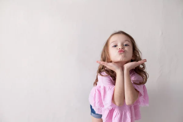 Una bambina in un abito rosa aria bacio — Foto Stock