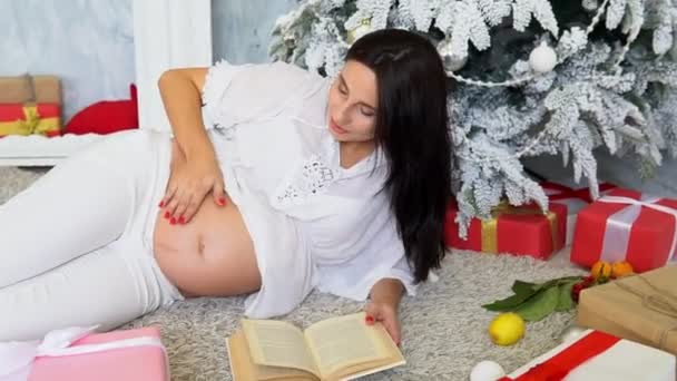 Gravid mamma av julgranen med julklappar — Stockvideo
