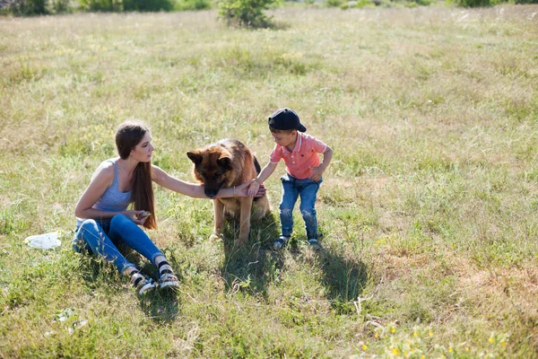 Madre e figlio giocare con un cane addestrato — Foto Stock