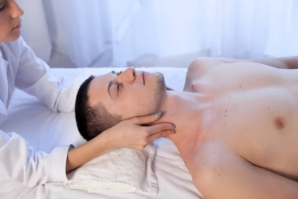 Um massagista faz um homem massagem terapia spa facial — Fotografia de Stock