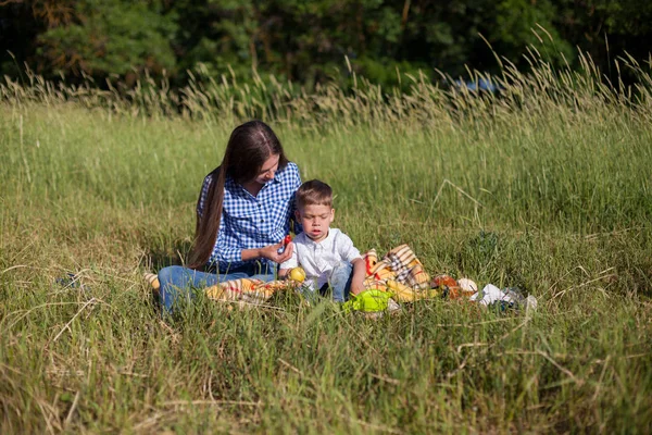 Portret matki z młodym synem jeść na piknik w lesie — Zdjęcie stockowe