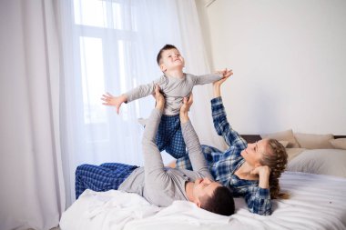 Anne baba ve oğlunun sabahları yatakta gülünecek bir aile oyna
