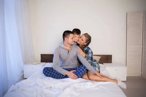 Mama Papa und kleiner Sohn spielen morgens im Bett eine lachende Familie — Stockfoto