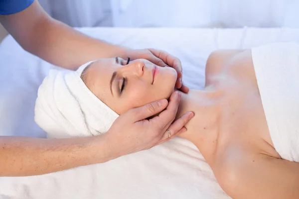 Een massagetherapeut maakt een vrouw gezicht en de hals massage in de Spa — Stockfoto
