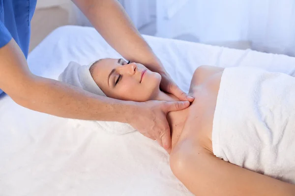 En massageterapeut gör en kvinna ansikte och nacke massage i Spa — Stockfoto