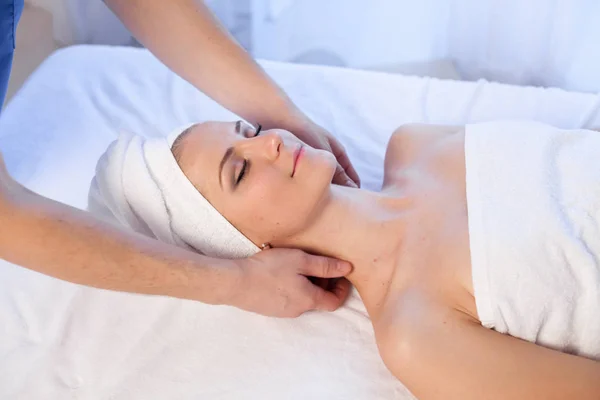 Een massagetherapeut maakt een vrouw gezicht en de hals massage in de Spa — Stockfoto