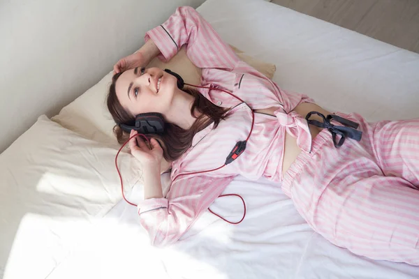 Vrouw Roze Pyjama Bilje Luistert Naar Muziek Met Koptelefoon — Stockfoto