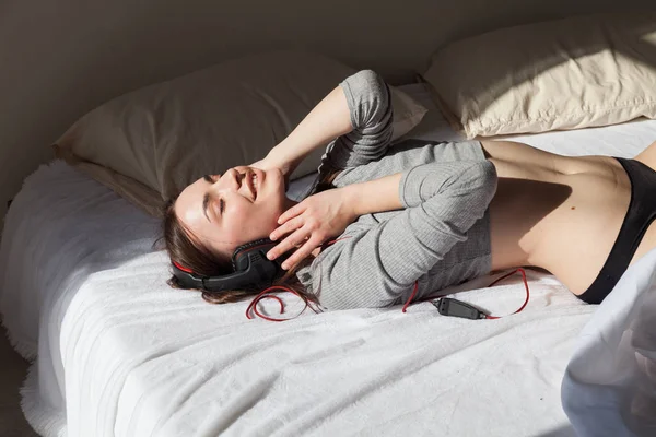 Vrouw in lingerie op bed, luisteren naar muziek — Stockfoto