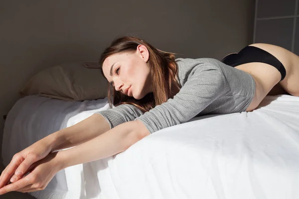 Mujer en lencería acostada en una cama en el dormitorio, retrato —  Fotos de Stock