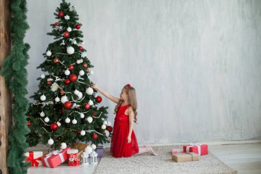 Kırmızı elbiseli küçük kız Noel hediyeleri yeni yıl tatili ile süslüdür