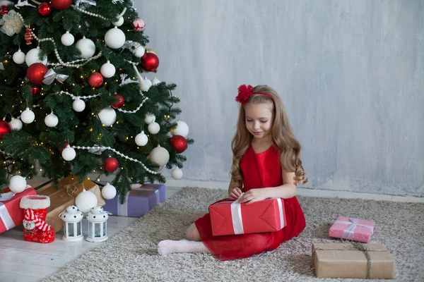 在圣诞树礼物新年假期的红色礼服的小女孩 — 图库照片