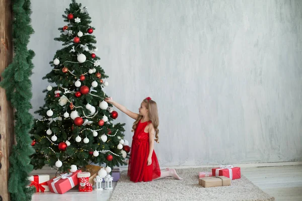 Mała dziewczynka w czerwonej sukience jest ozdobiony dary Boże Narodzenie nowy rok — Zdjęcie stockowe