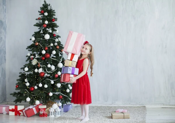 Маленькая девочка в красном платье на новогодние подарки елки — стоковое фото