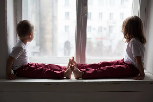 küçük erkek ve kız pencereden dışarı bakarak pencere oturmak