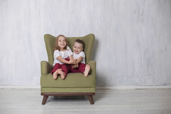 어린 소년과 소녀는 형제와 자매는 녹색의 자에 앉아 — 스톡 사진