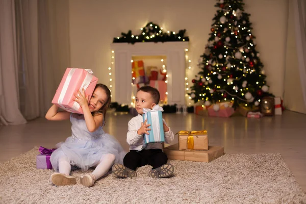 Menino e menina abrem presentes de Natal Ano Novo inverno árvore de Natal — Fotografia de Stock