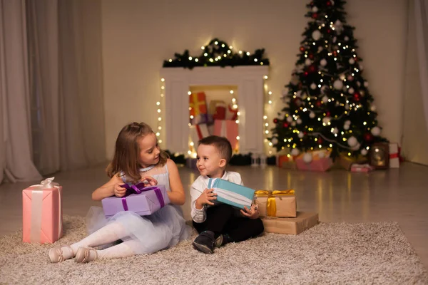 Niño y niña abren regalos de Navidad año nuevo árbol de Navidad de invierno — Foto de Stock