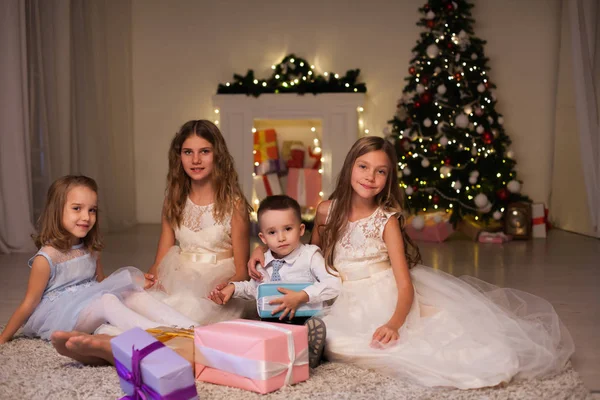 O menino e três meninas crianças abrem presentes de Natal árvore de Natal de inverno do ano novo — Fotografia de Stock