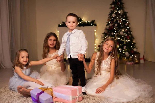 O menino e três meninas crianças abrem presentes de Natal árvore de Natal de inverno do ano novo — Fotografia de Stock