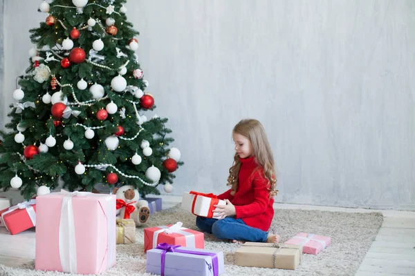 Маленькая девочка в красном платье на новогодние подарки елки — стоковое фото