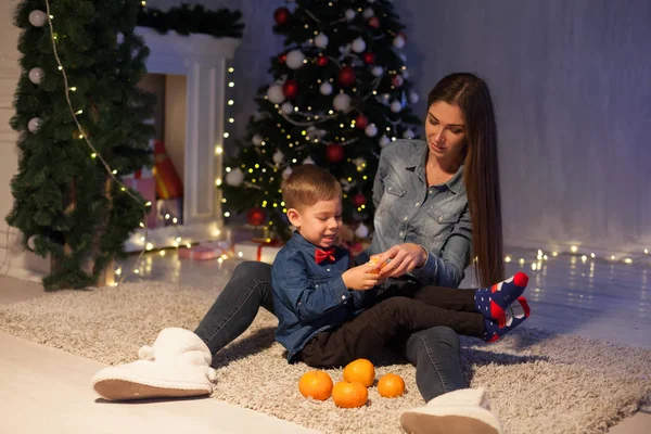 Moeder met de zonen eten mandarijnen Nieuwjaar kerstboom geschenken — Stockfoto