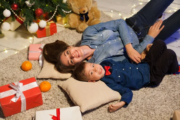 Mère et jeune fils sont à l'arrière d'un arbre de Noël avec des cadeaux — Photo