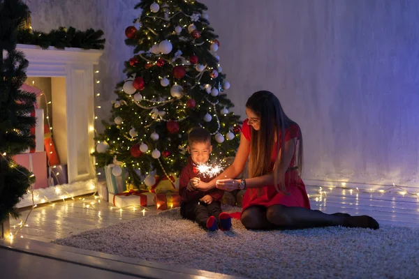 Мать и сын празднуют Новый год у елки с подарками гирлянды огни — стоковое фото