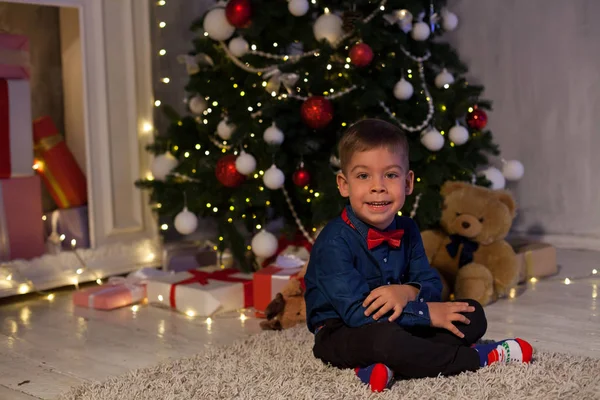 Мальчик открывает рождественские подарки новогодние гирлянды — стоковое фото