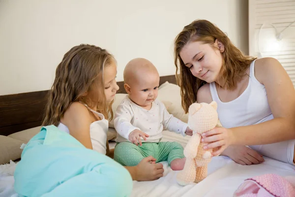Three girls sisters in the morning in the bedroom on the bed play — Stock Photo, Image