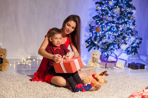 Mamá con hijo decorar árbol de Navidad regalos de año nuevo luces de guirnalda — Foto de Stock